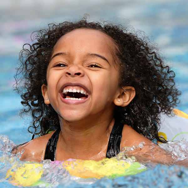 A young girl laughs as she plays in the water.