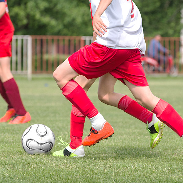 Two boys jockey for the ball in a game of soccer.