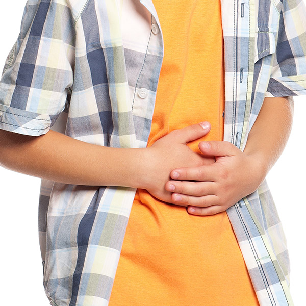 A young boy places two hands on his stomach.