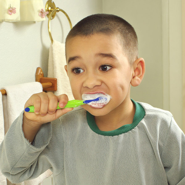 A young boy brushes his teeth with vigor.