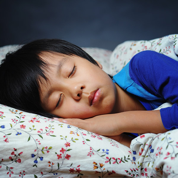 A young boy sleeps peacefully in his bed.