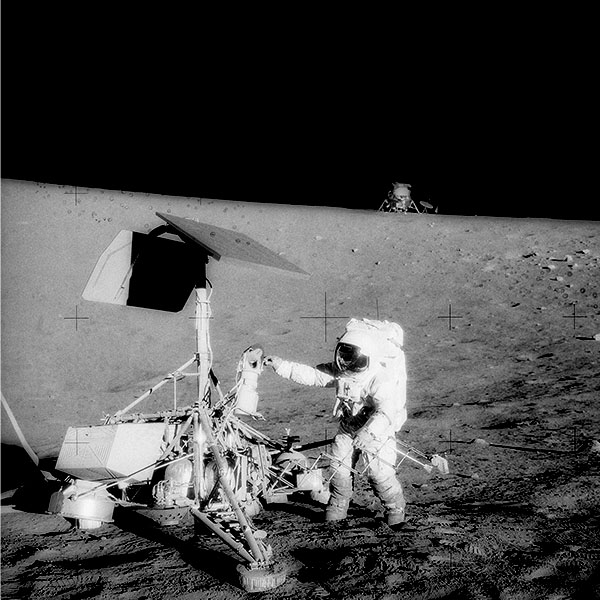 An Astronaut on the moon adjusts a retroreflector.