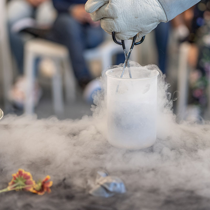 Person using tongs to remove objects from a beaker filled with liquid nitrogen.